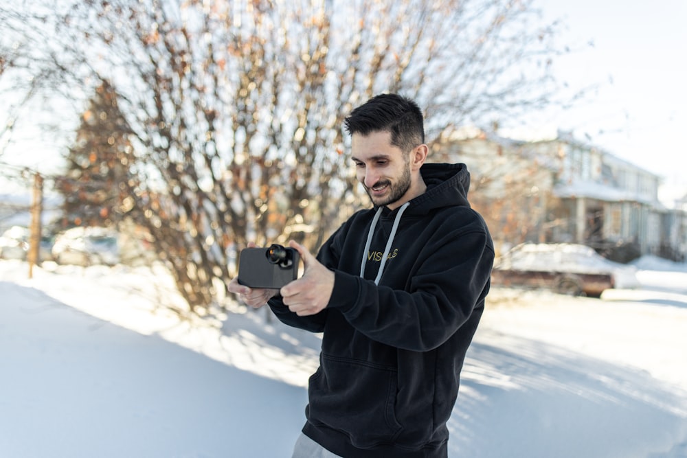 um homem de pé na neve segurando uma câmera