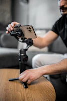 Close-up of a smartphone mounted on a gimbal capturing natural light in a cozy indoor setting.