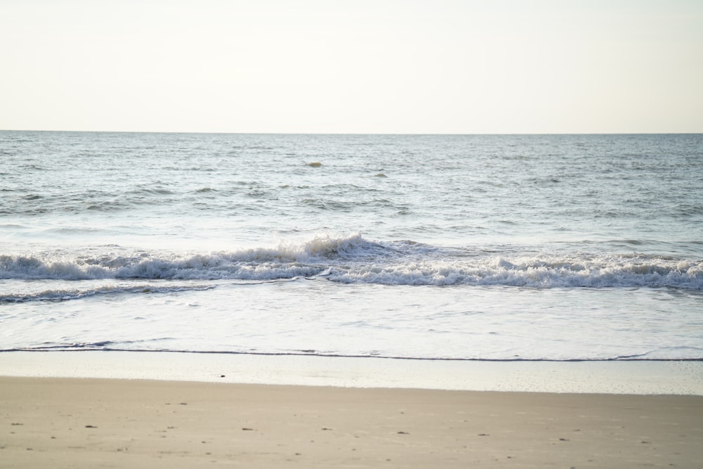 a person walking along the beach with a surfboard