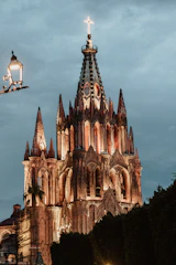 a large cathedral lit up at night under a cloudy sky
