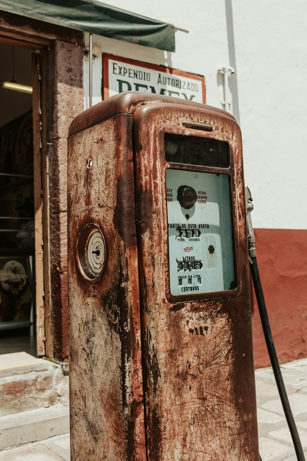 an old rusty gas pump on the side of the road