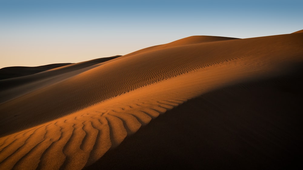 a sand dune with a blue sky in the background