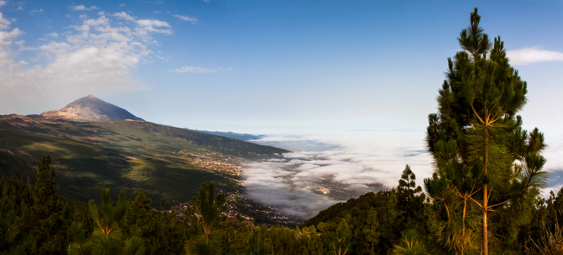 a view of a mountain with clouds below