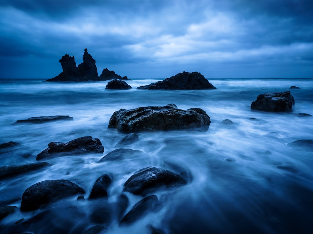 a long exposure photo of rocks in the ocean