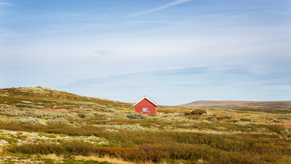 a red house on a hill with a blue sky in the background