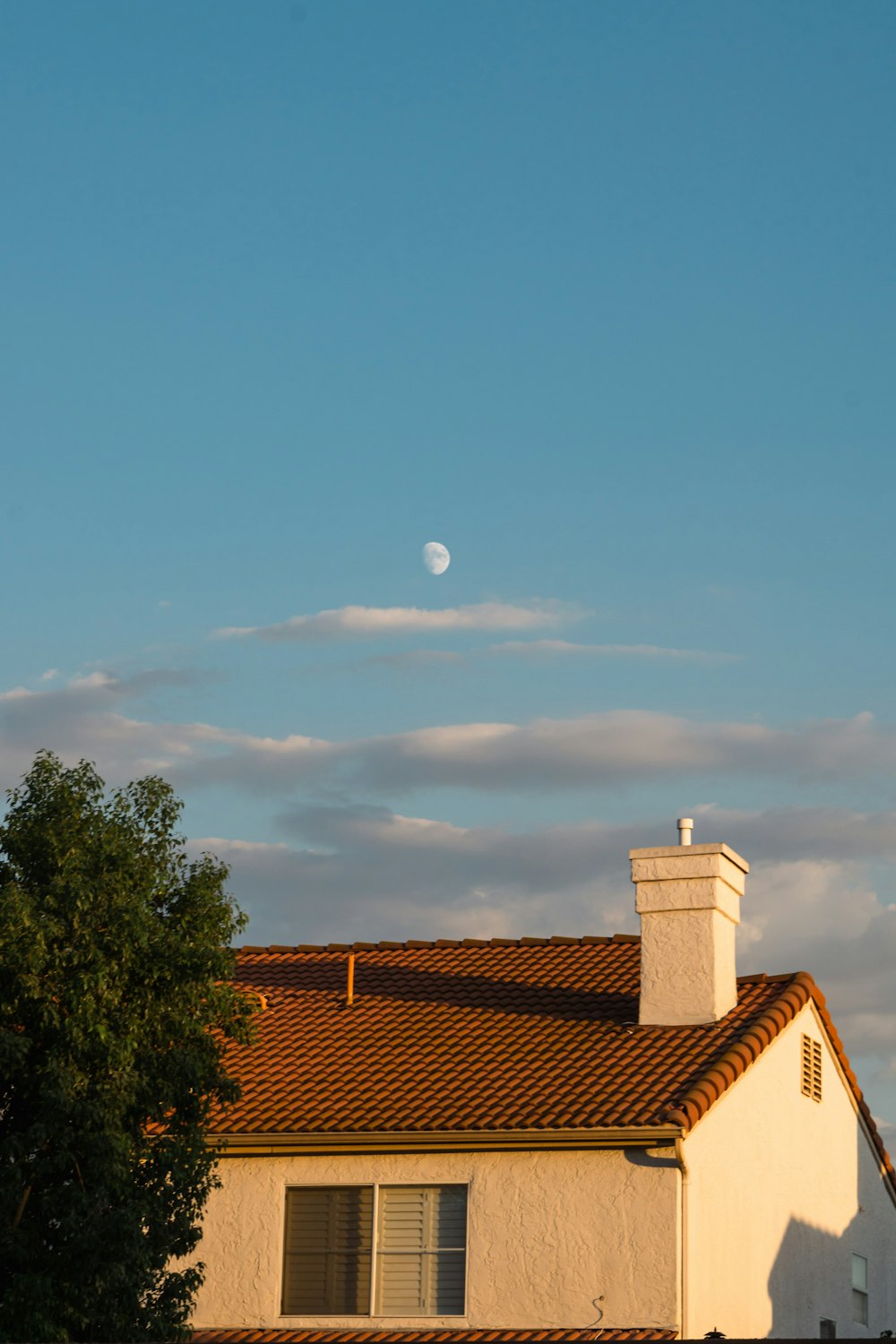 a house with a clock tower and a full moon in the sky