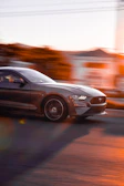 Dynamic side view of a metallic gray concept car speeding on an open road at dusk.