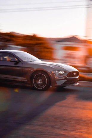 A cinematic shot of a sleek sports car speeding on a racetrack at dusk, with motion blur emphasizing its power.