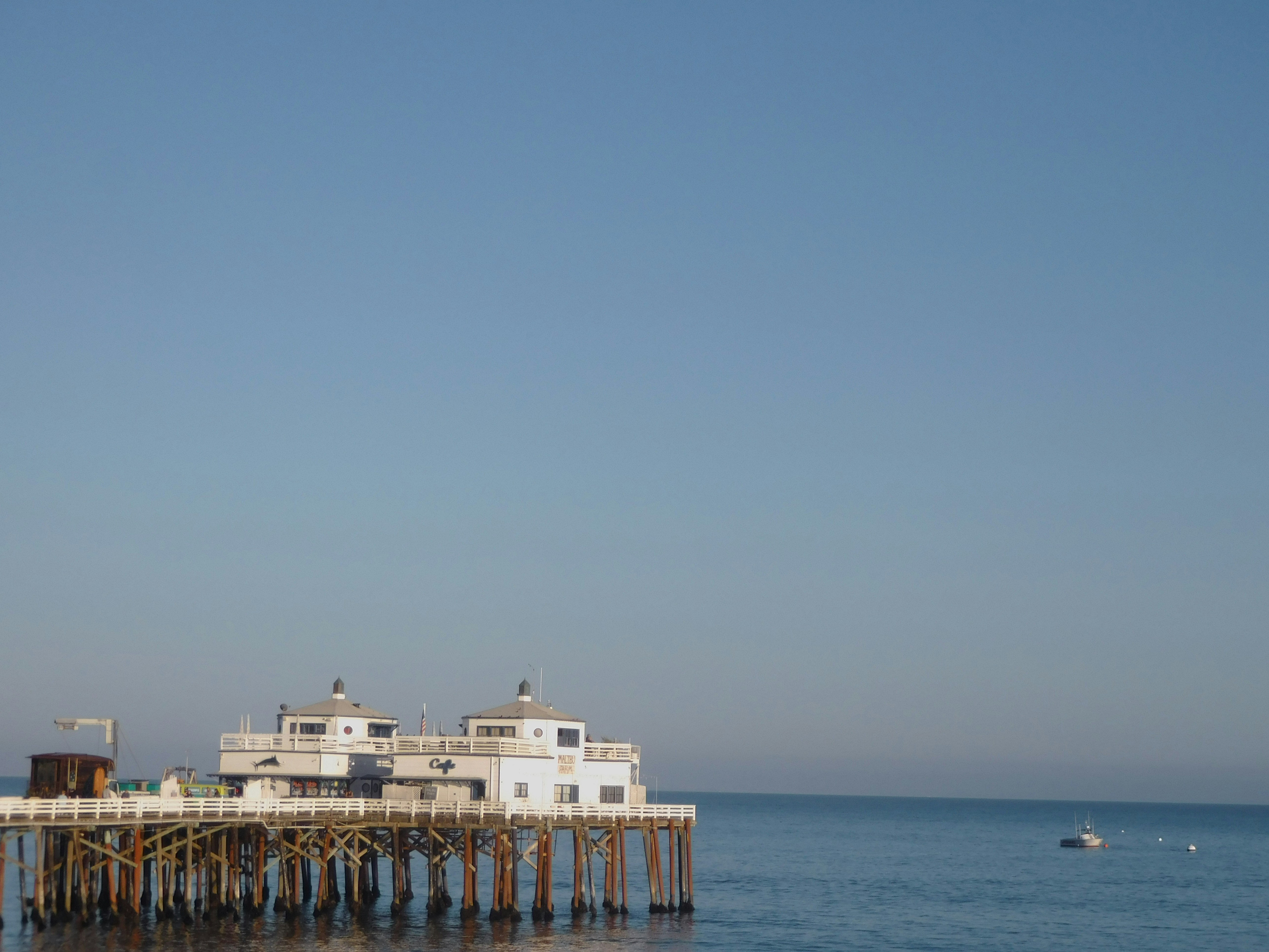 a pier in the middle of the ocean with a boat in the water