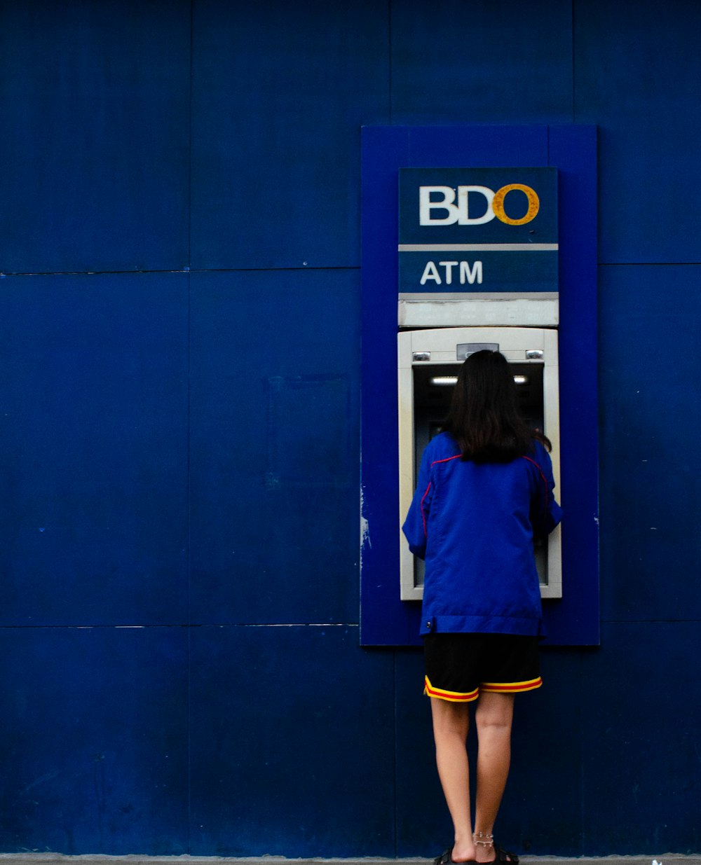 a woman standing in front of a blue atm machine
