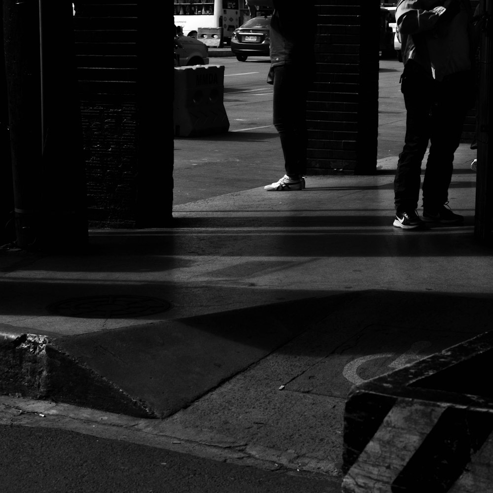 two people standing on a sidewalk next to a building