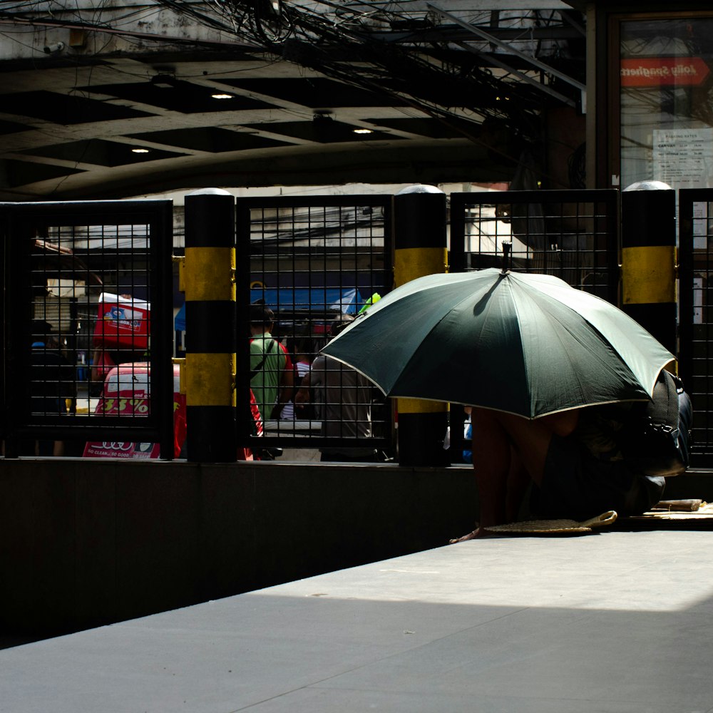 a person sitting under an umbrella on a platform