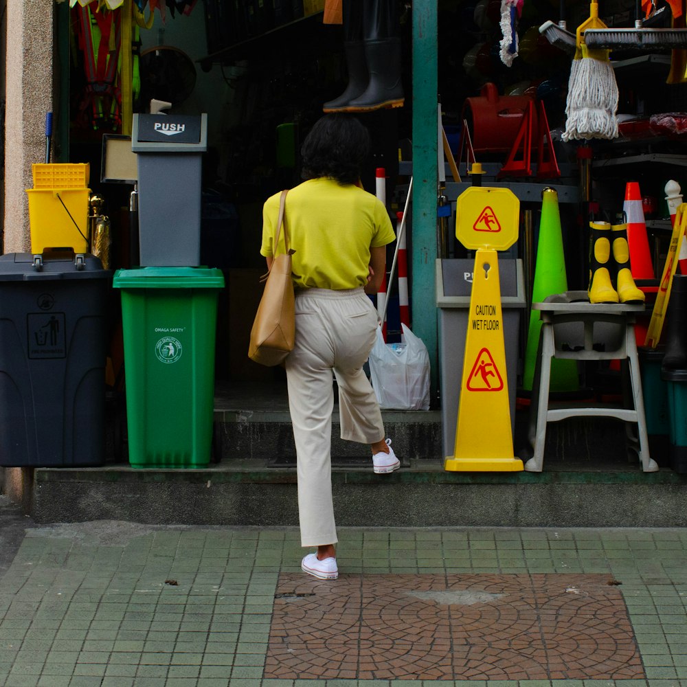 a woman in a yellow shirt is walking by a store