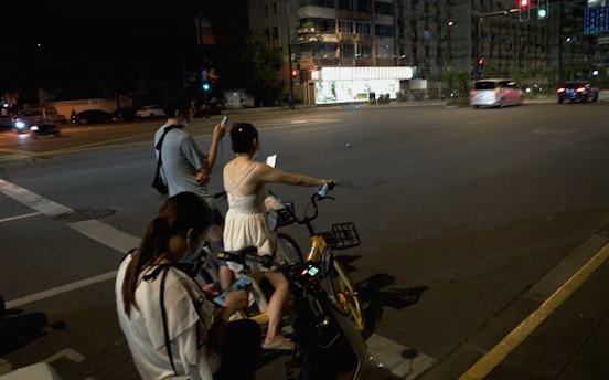 a group of people riding bikes down a street at night