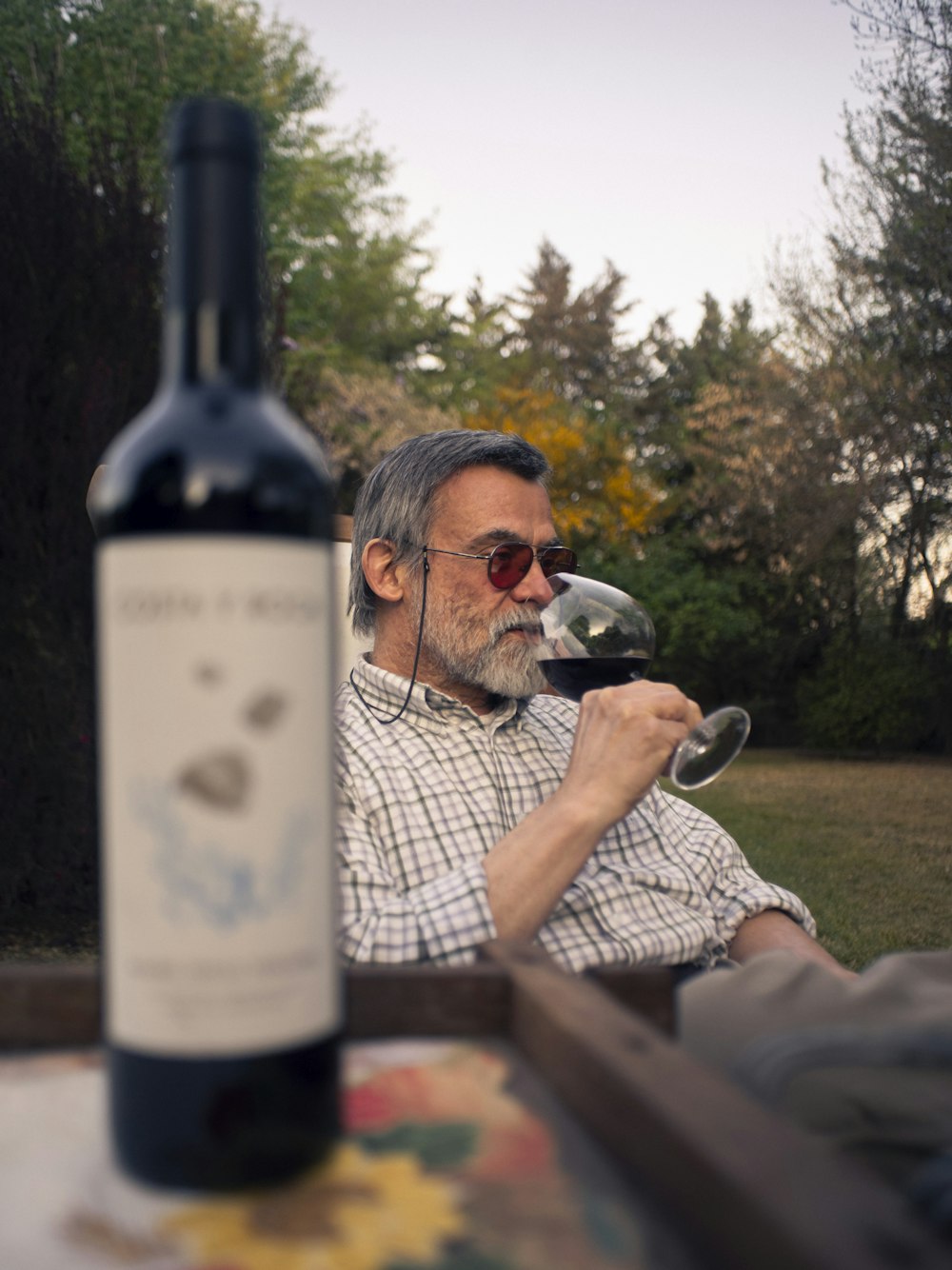 a man sitting at a table with a bottle of wine
