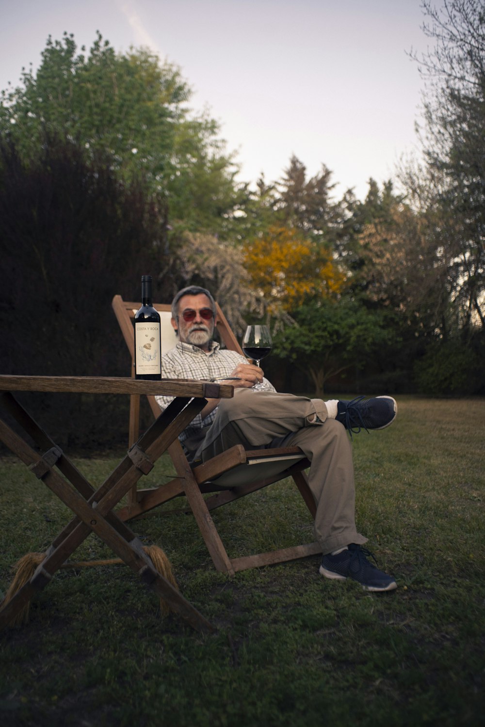 a man sitting at a picnic table with a bottle of wine