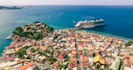Scenic view of a cruise ship approaching the colorful houses of a coastal European town.