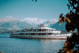 Tourists enjoying a boat ride on a crystal-clear lake surrounded by snow-capped peaks.