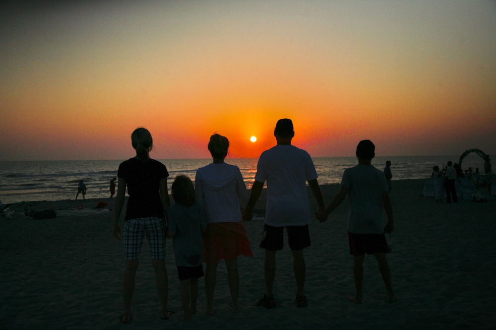 a group of people standing on top of a sandy beach