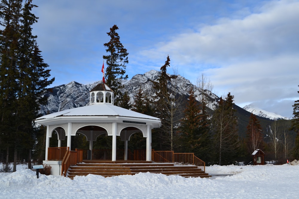a gazebo in the snow with mountains in the background