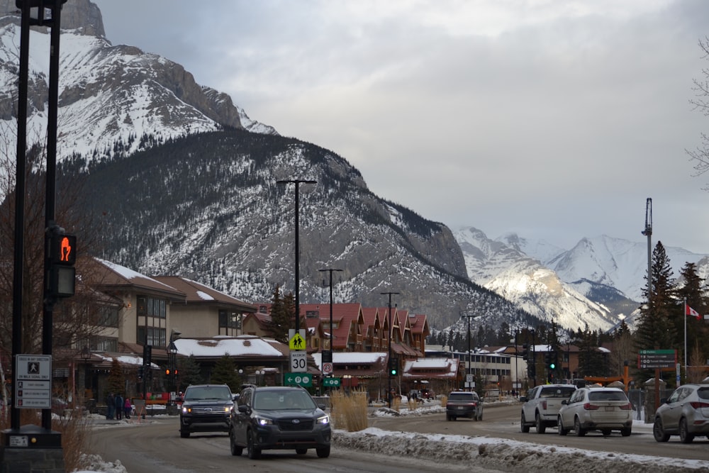 a street filled with lots of traffic next to a snow covered mountain