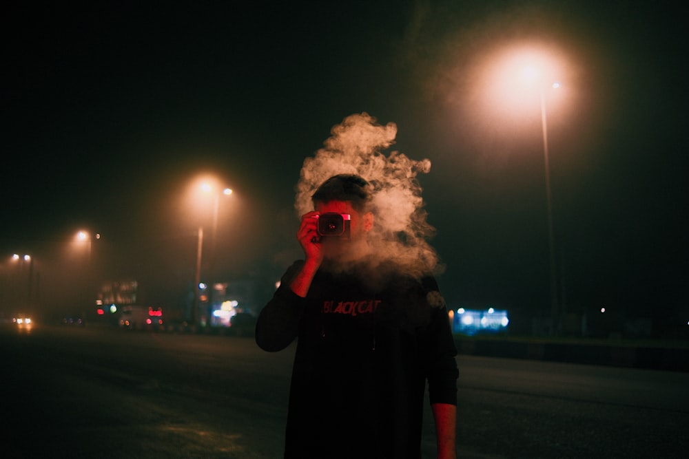 a man smoking a cigarette on a street at night