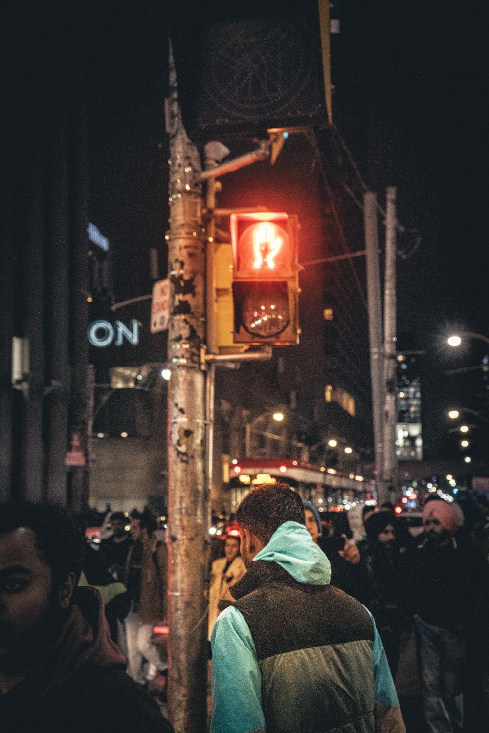 uma multidão de pessoas em pé em uma rua ao lado de um semáforo