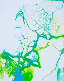 Vibrant abstract patterns with intertwining blue and green lines resembling organic shapes or cells against a white background. The design has fluid, flowing forms that blend smoothly into each other, creating a sense of movement and complexity.