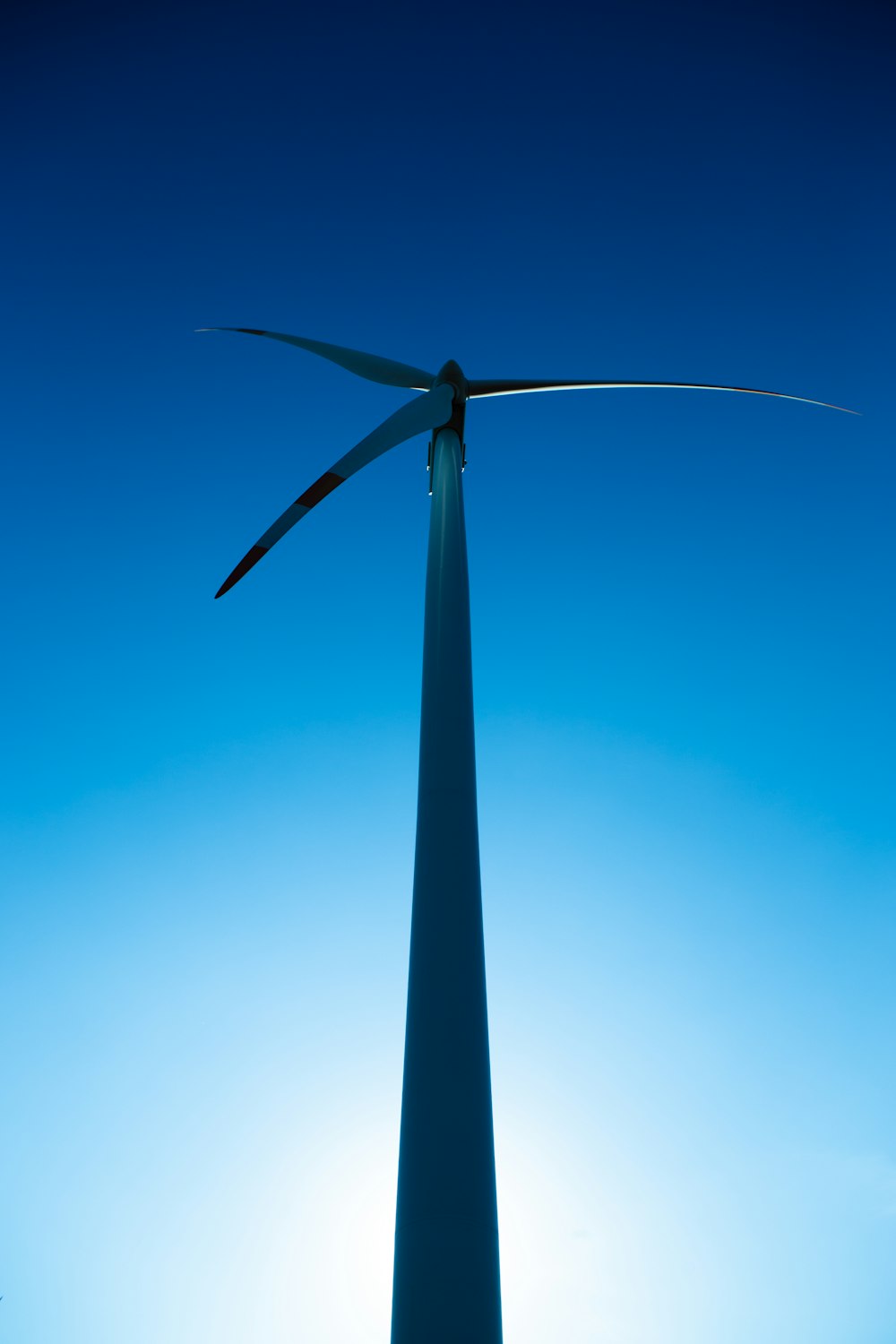 a wind turbine is silhouetted against a blue sky