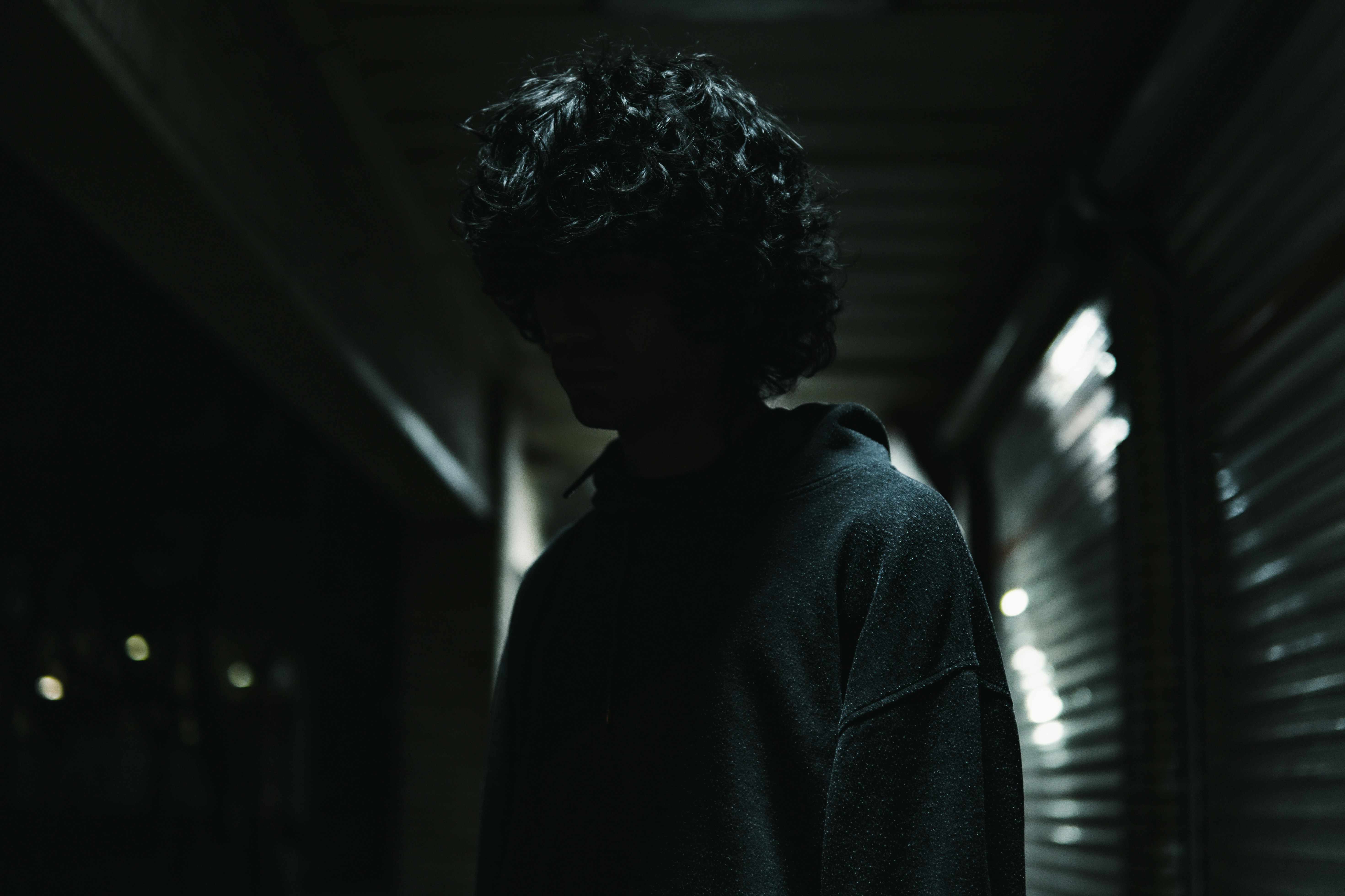 a man standing in a dark hallway with his hands in his pockets