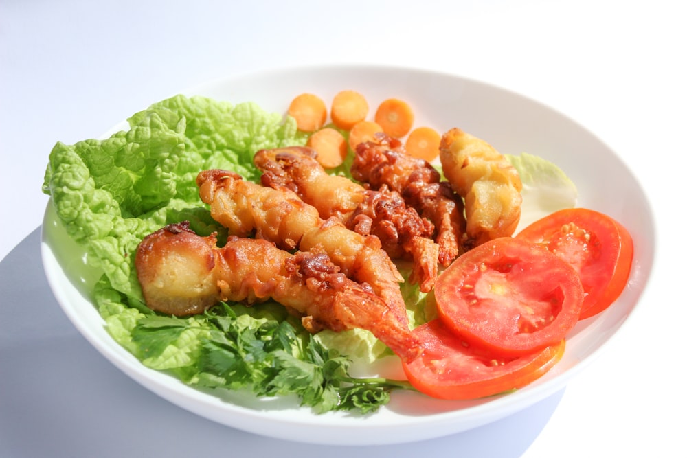 a white plate topped with lettuce and tomatoes