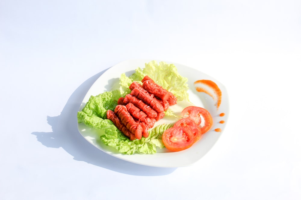 a white plate topped with lettuce and tomatoes