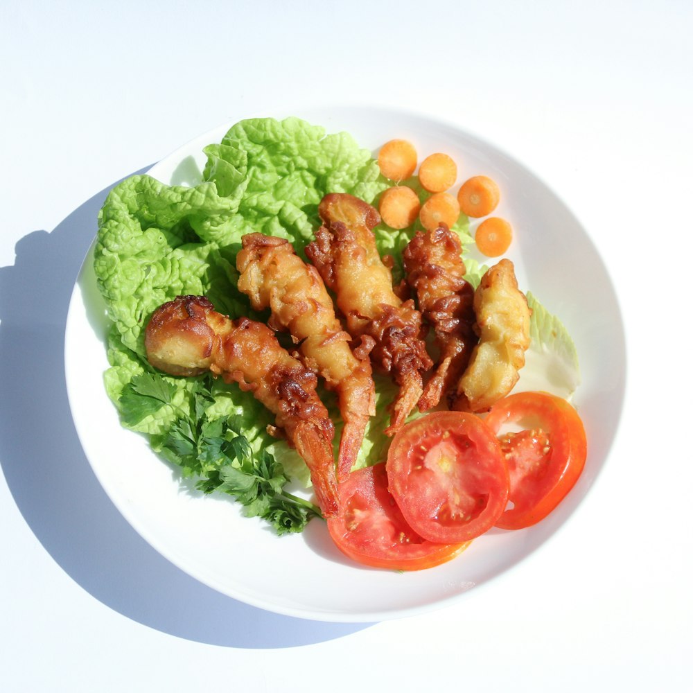 a white plate topped with lettuce and tomatoes