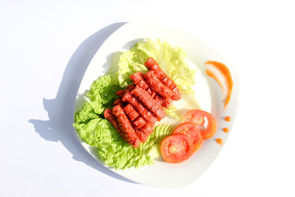 a white plate topped with lettuce and tomatoes