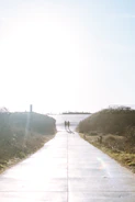 Footsteps on a path leading toward a bright horizon.
