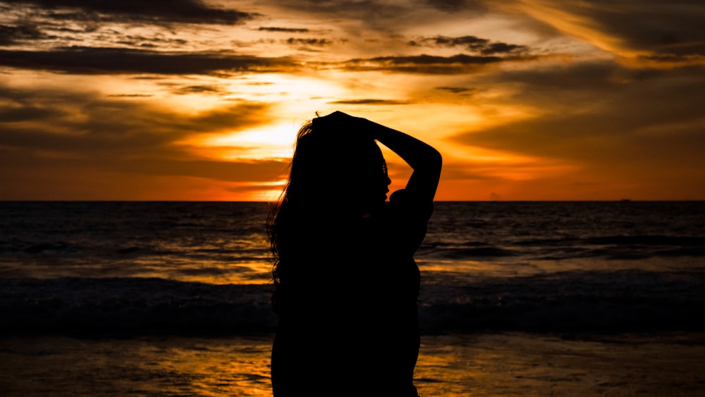 a woman standing on a beach at sunset