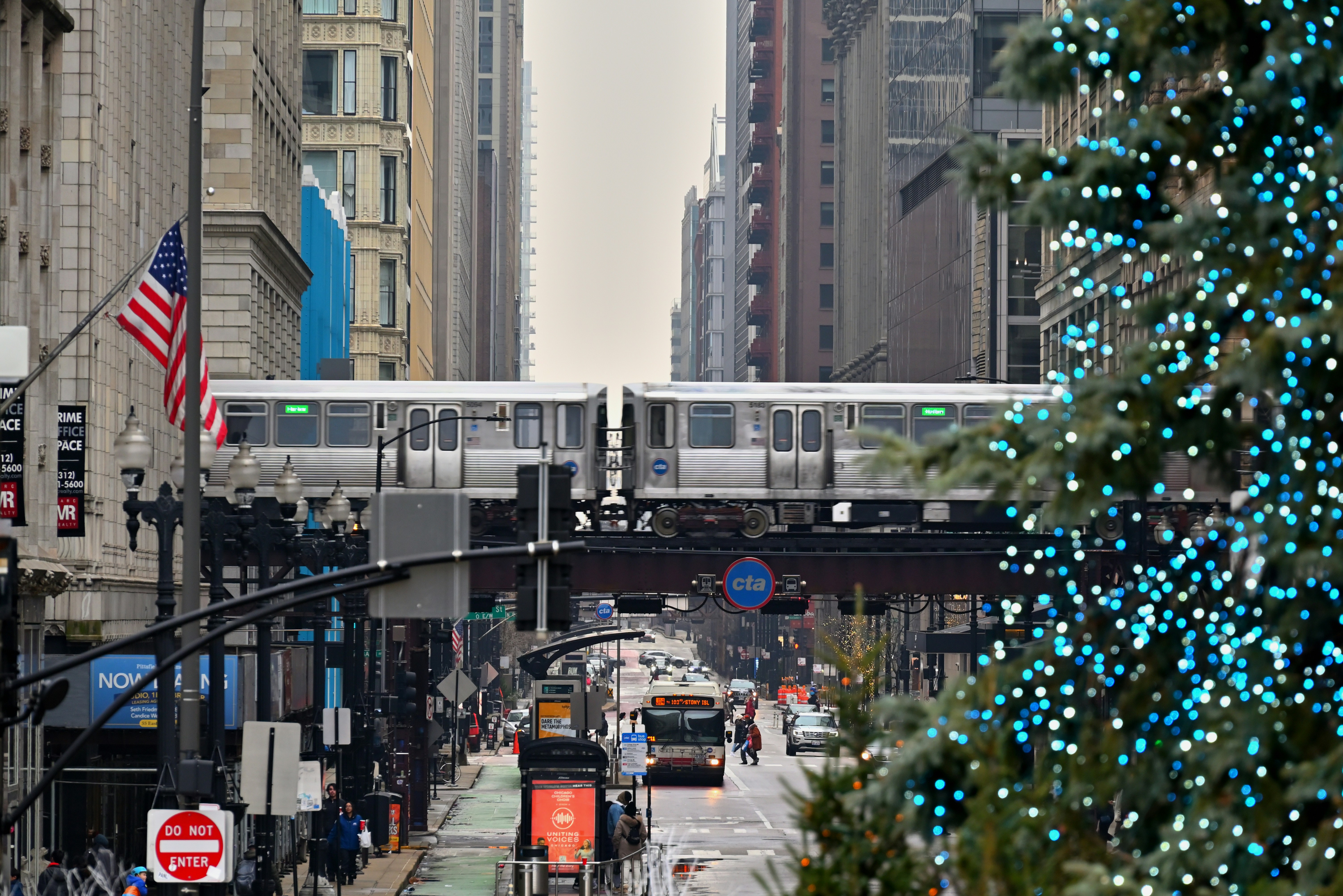 a city street with a christmas tree and a train on the tracks