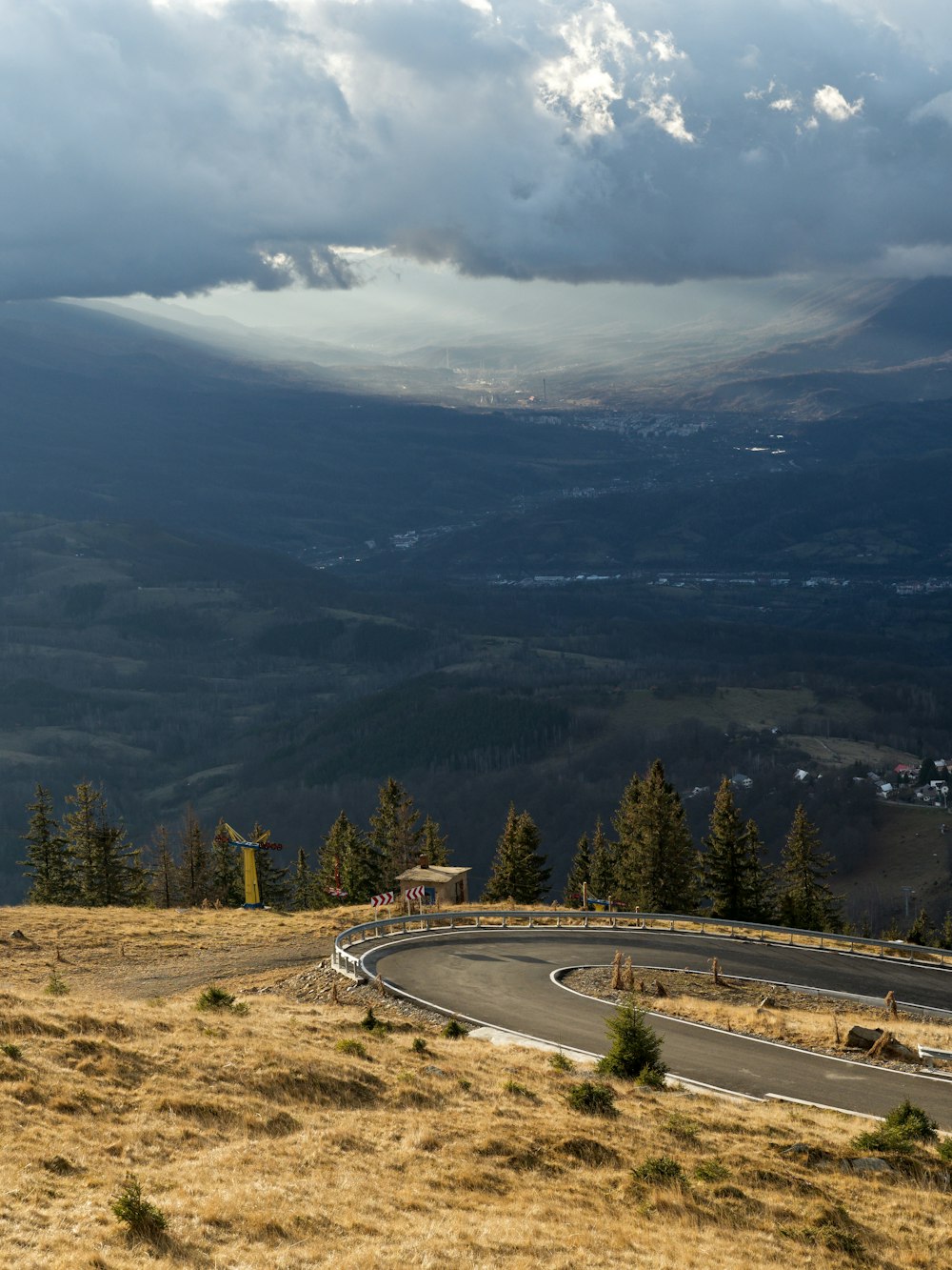 a winding road in the mountains under a cloudy sky