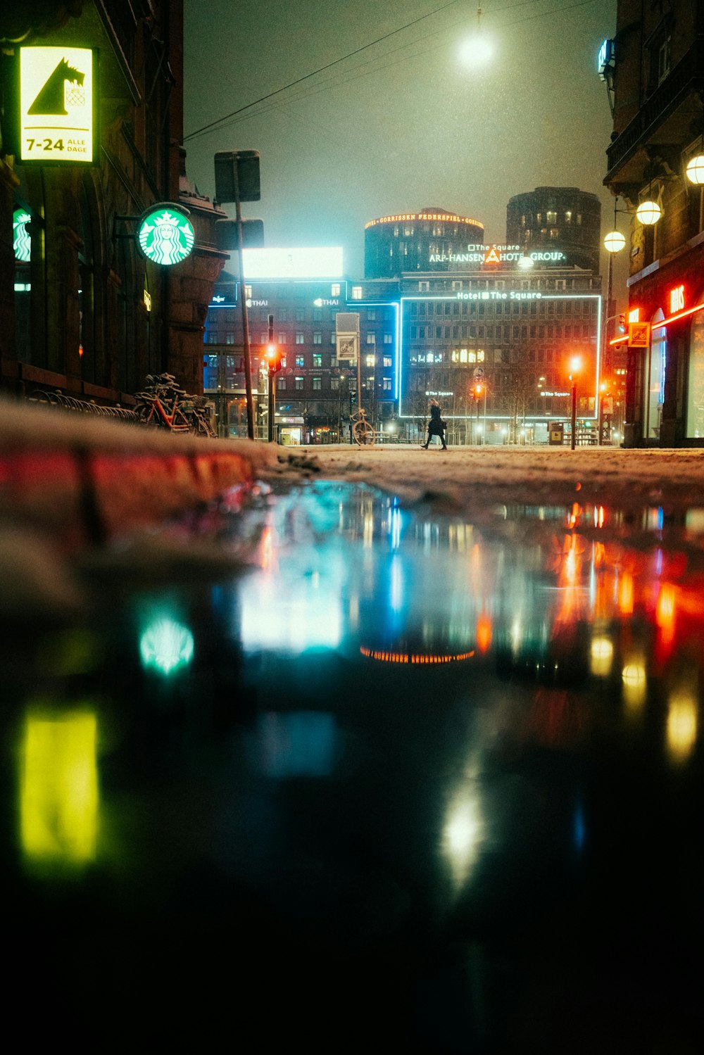 a city street at night with lights reflecting in the water