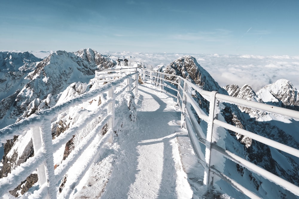 ein schneebedeckter Berg mit weißem Zaun