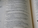 An open book with visible text on its pages, featuring several sentences in a serif typeface. The text contains a title in bold, indicating a prophecy against the Philistines, followed by numbered verses that appear to be from a biblical or religious context. The page edges are slightly curved, emphasizing the book's thickness and texture.