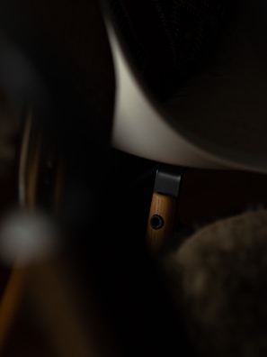 Detail shot of a sturdy desk leg with black metal accents against a beige background.