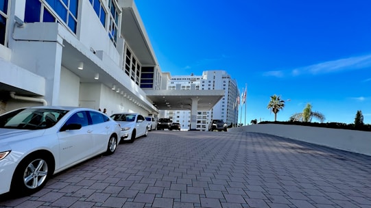 A modern hotel entrance with guests arriving and parking their cars.