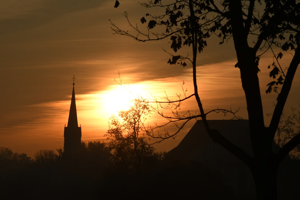 the sun is setting behind a church steeple