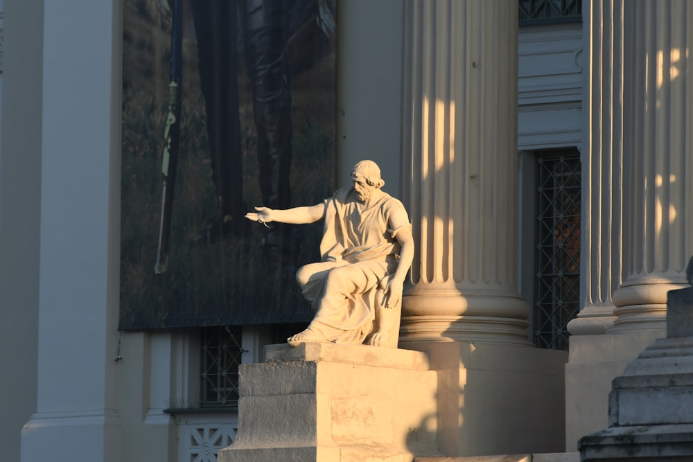 a statue of a man sitting on top of a pillar