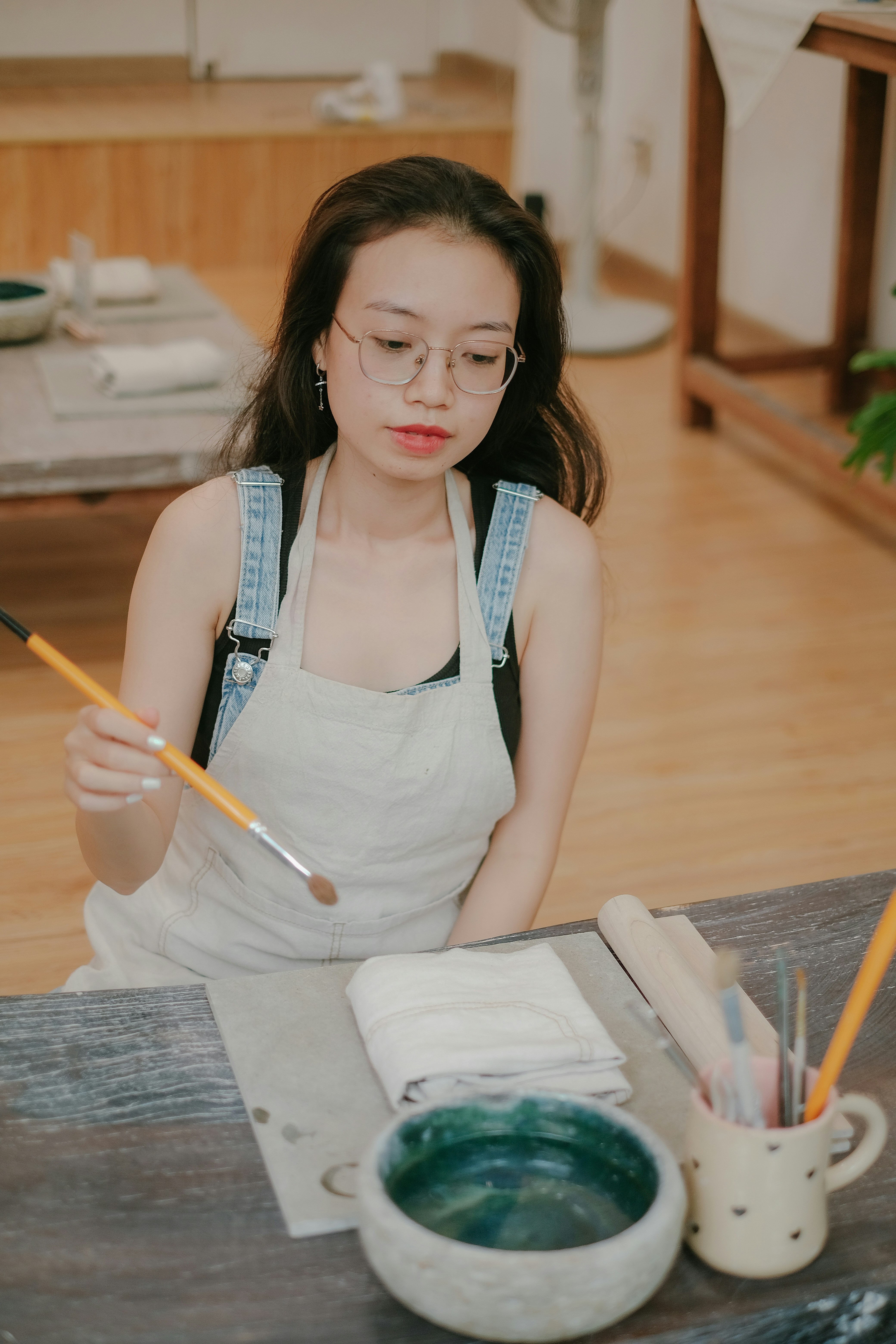 a woman in an apron painting a picture on a table