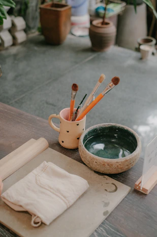 Various painting tools including brushes and rollers neatly arranged on a wooden table.