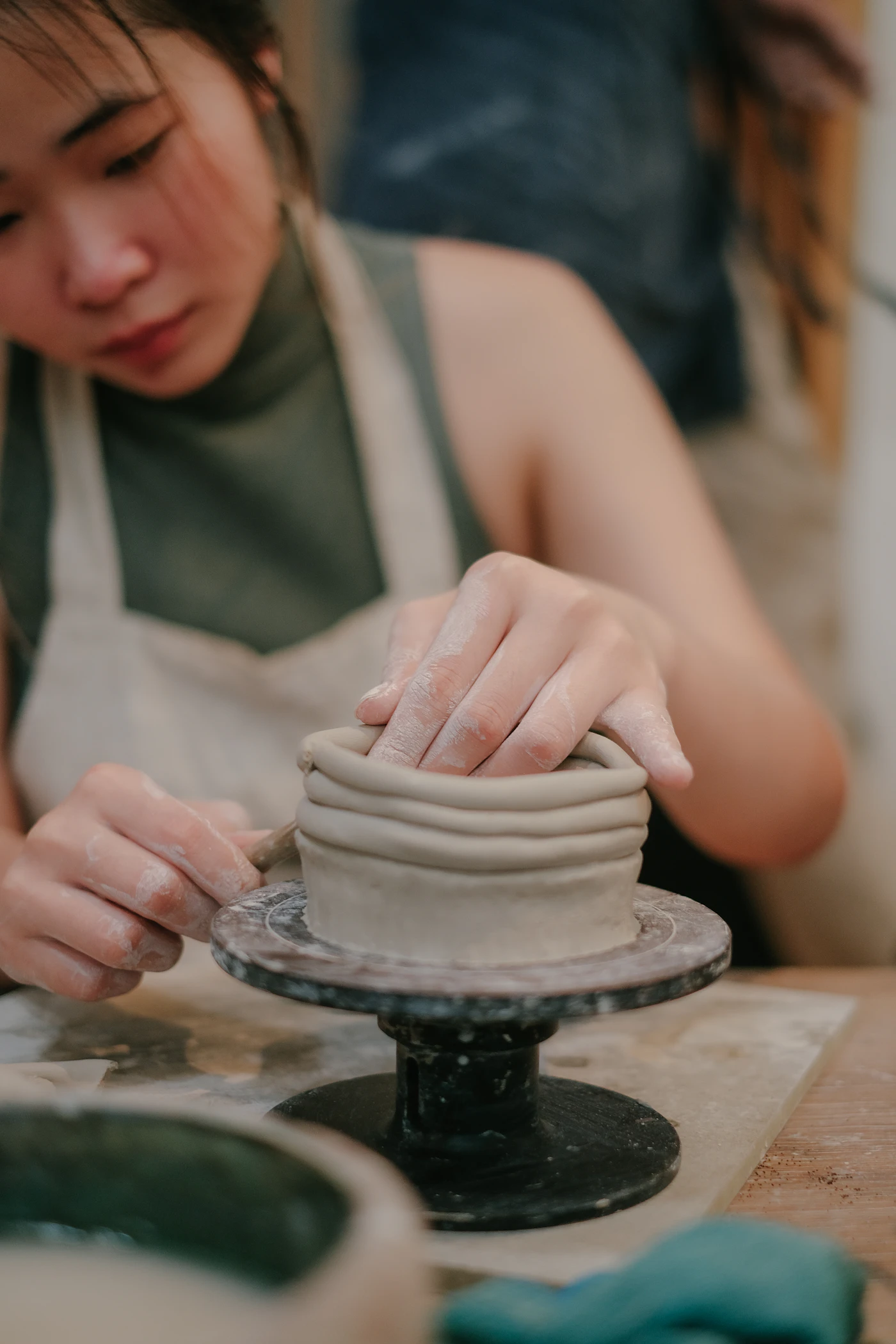 A woman shaping a small clay pot by hand