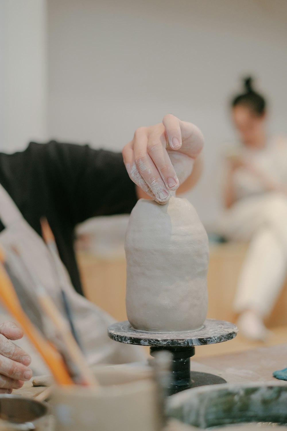 a woman is working on a clay sculpture