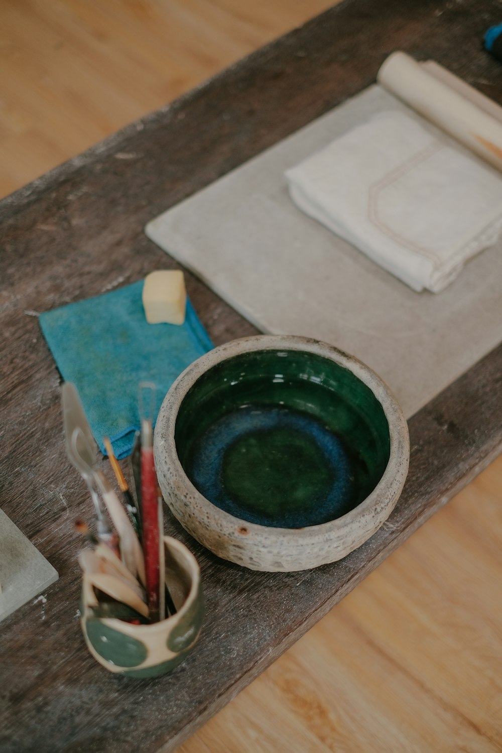 a wooden table topped with a green bowl filled with paint